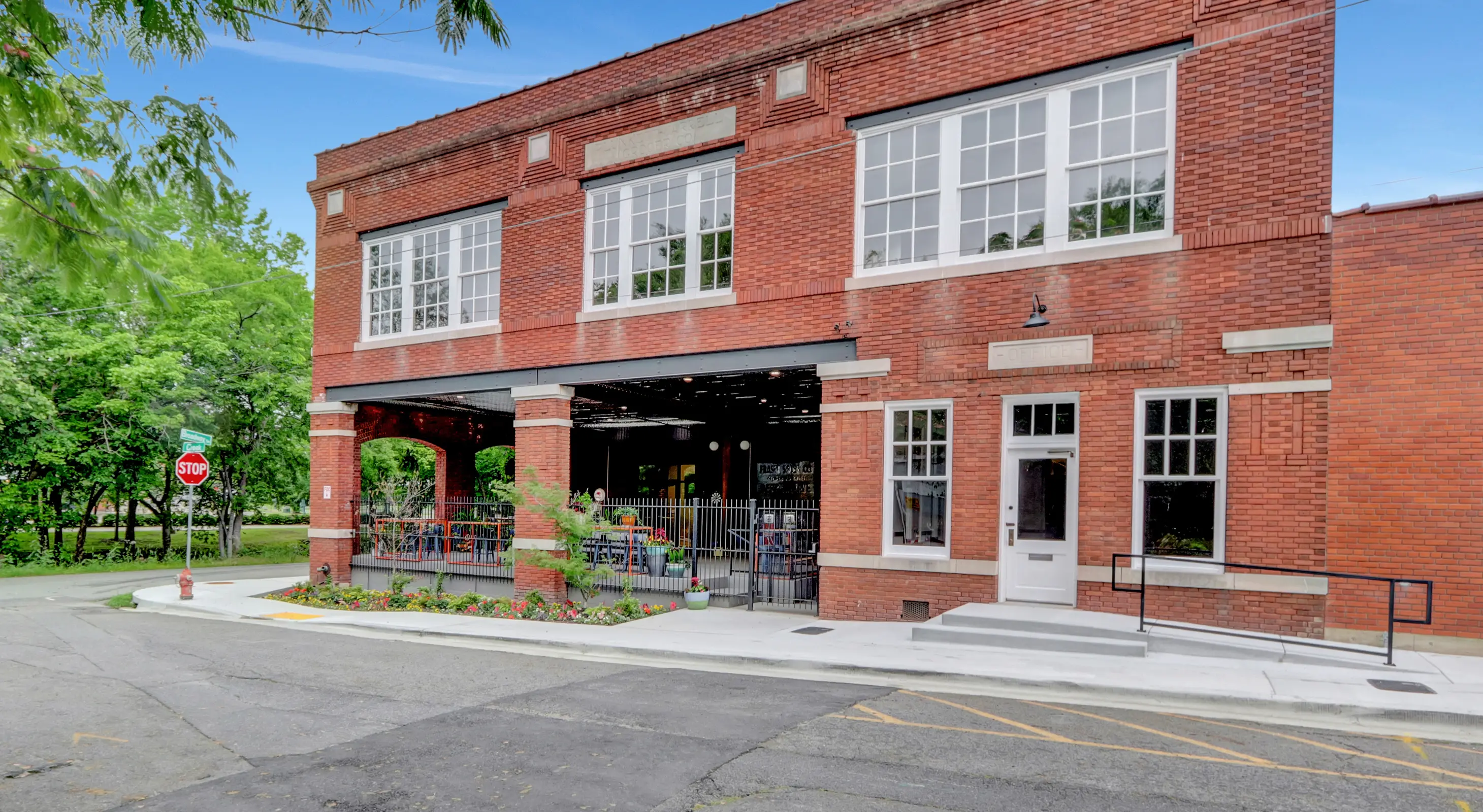 Front facade of Lofts at Creek Street featuring large historic windows and an open-air lower-level space surrounded by greenery in downtown Hot Springs