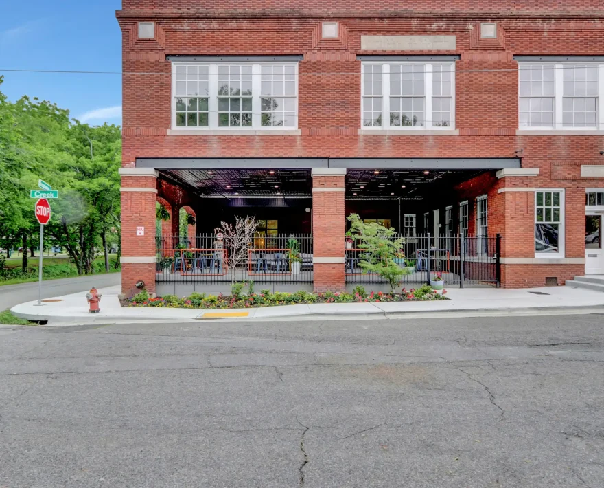 Exterior view of Lofts at Creek Street with brick architecture, open patio seating, and landscaped walkways along Creek Street