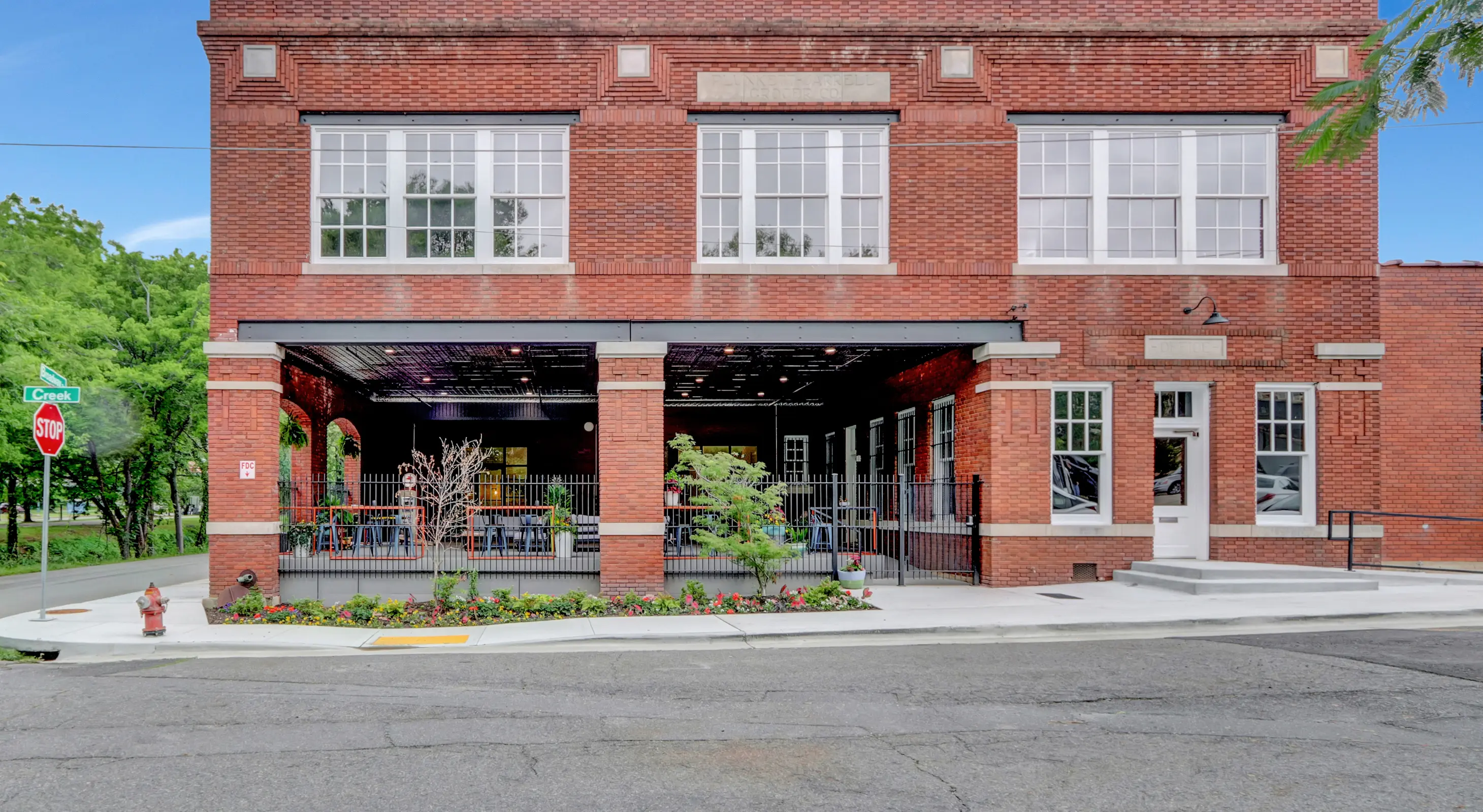 Exterior view of Lofts at Creek Street with brick architecture, open patio seating, and landscaped walkways along Creek Street