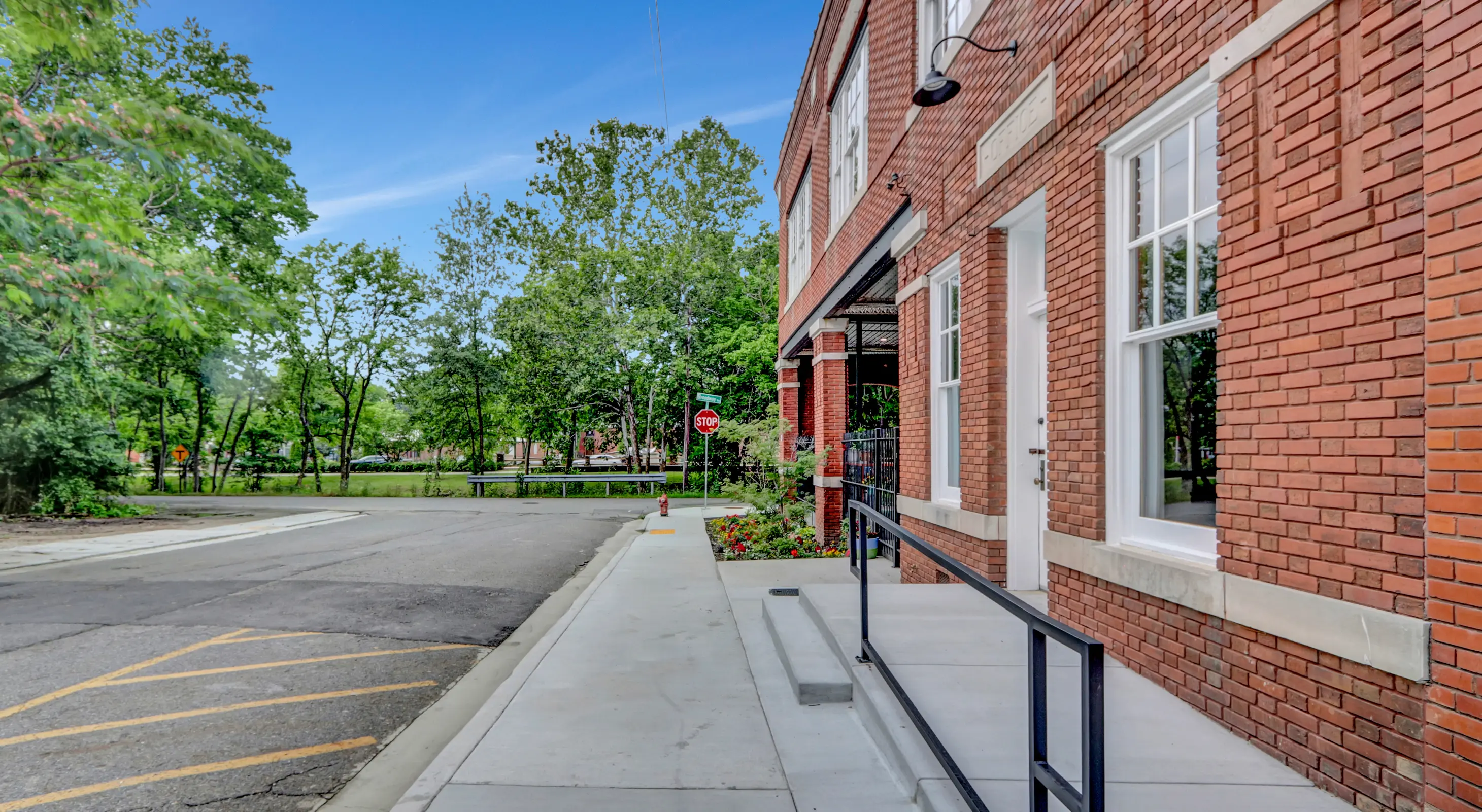 Exterior view of Lofts at Creek Street along Creek Street, showing the historic brick facade and tree-lined park directly across from the building