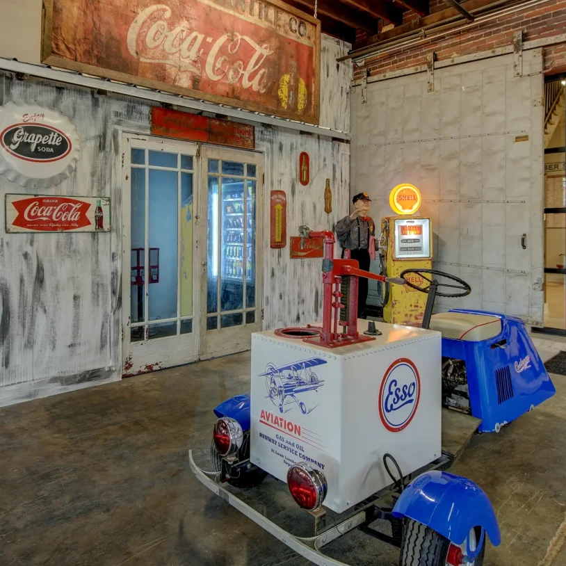 Ground-level common area at Lofts at Creek Street with restored vintage Coca-Cola signage, retro vending display, and historic gas-station decor