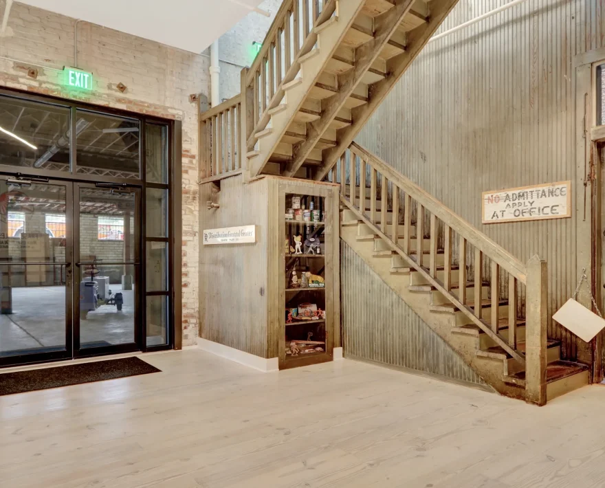 Historic foyer at Lofts at Creek Street featuring original staircase, exposed brick, vintage signage, and industrial-style restoration details