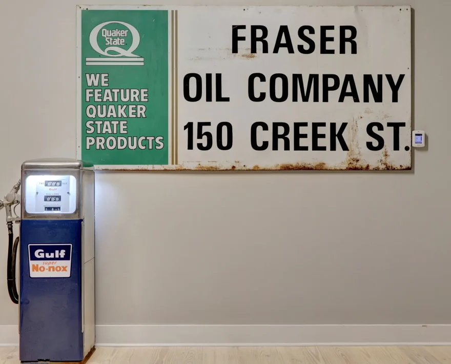 Vintage Gulf gas pump displayed inside Lofts at Creek Street alongside original Fraser Oil Company sign from the building’s historic use