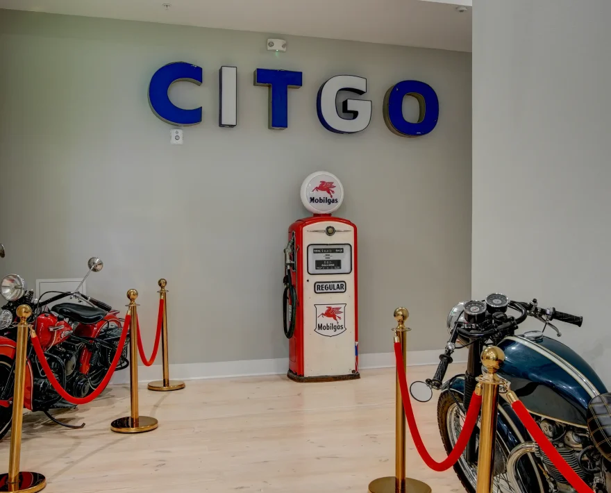 Restored hallway at Lofts at Creek Street featuring vintage motorcycles, a Mobilgas pump, and CITGO wall signage from the building’s industrial past