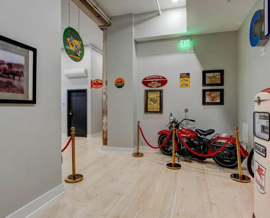 Interior display area at Lofts at Creek Street showcasing vintage motorcycles, Mobilgas pump, and historic automotive signage