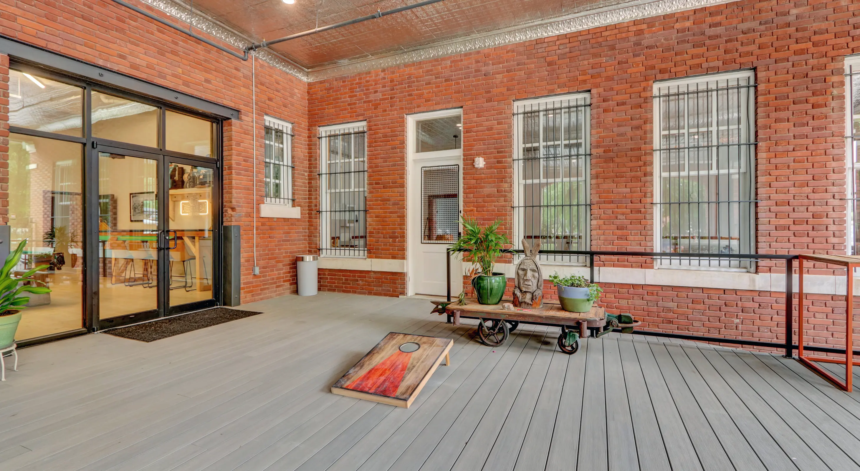 Accessible patio with cornhole and greenery within a restored brick building offering boutique accommodations