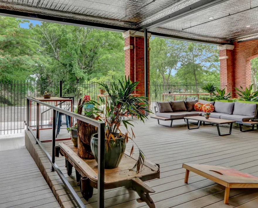 Accessible outdoor patio with lounge seating and potted plants at a renovated industrial brick lodging property