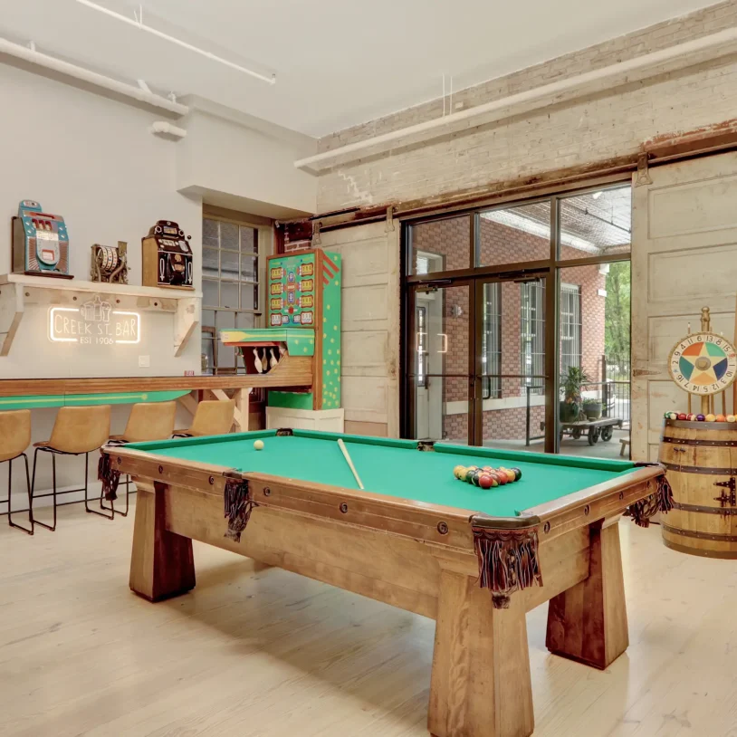 Boutique lodging game room with a reclaimed-wood pool table, vintage game machines, and a retro-inspired bar area