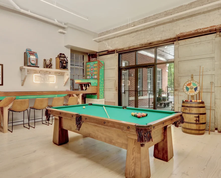Boutique lodging game room with a reclaimed-wood pool table, vintage game machines, and a retro-inspired bar area