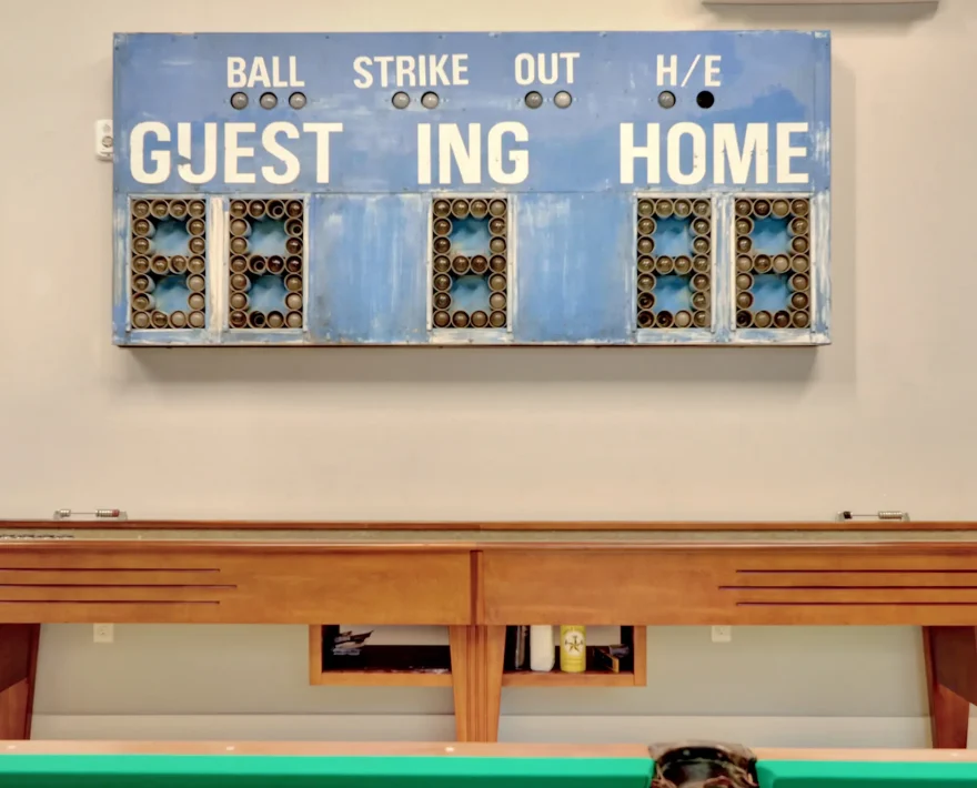 Guest entertainment space featuring a classic shuffleboard table and vintage scoreboard inside a converted industrial-style accommodation