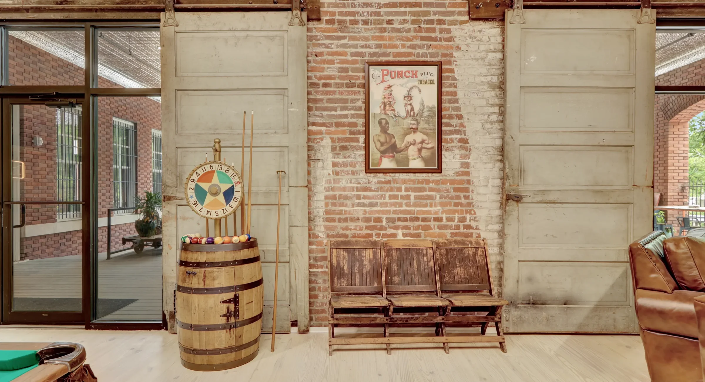 Historic interior wall with original brick, sliding industrial doors, vintage barrel décor, and guest seating inside a renovated loft accommodation