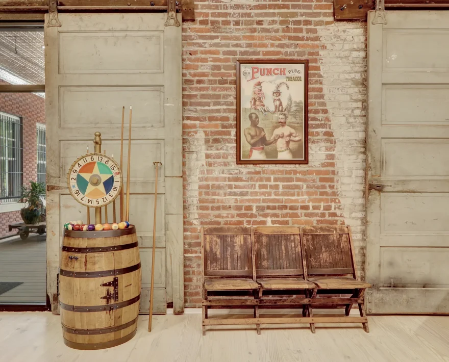 Historic interior wall with original brick, sliding industrial doors, vintage barrel décor, and guest seating inside a renovated loft accommodation