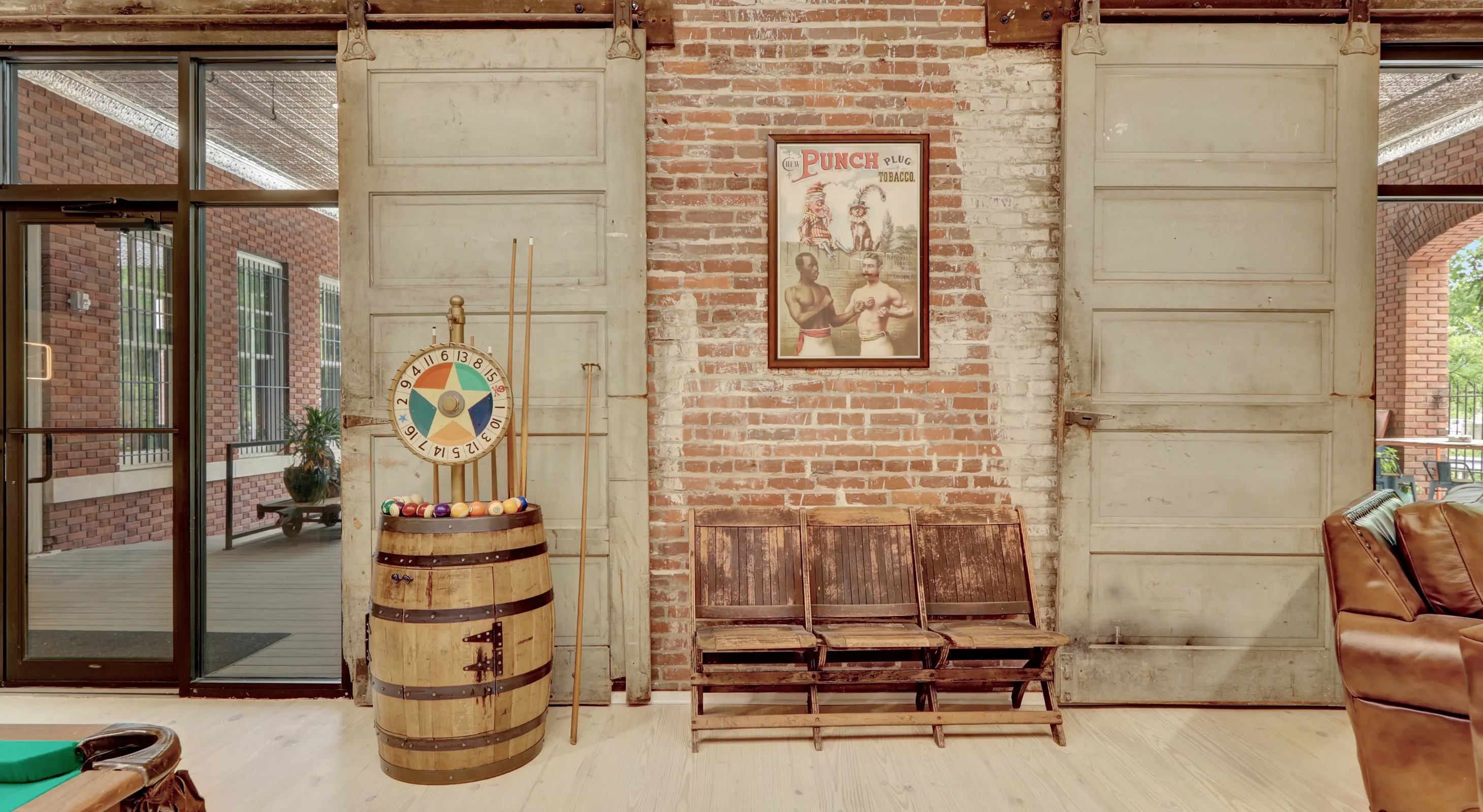 Historic interior wall with original brick, sliding industrial doors, vintage barrel décor, and guest seating inside a renovated loft accommodation.