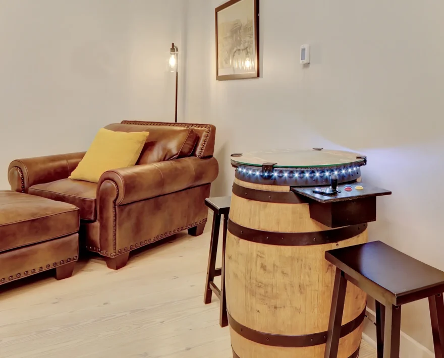 Retro-style arcade table made from a reclaimed barrel, paired with lounge seating inside a boutique loft-style accommodation