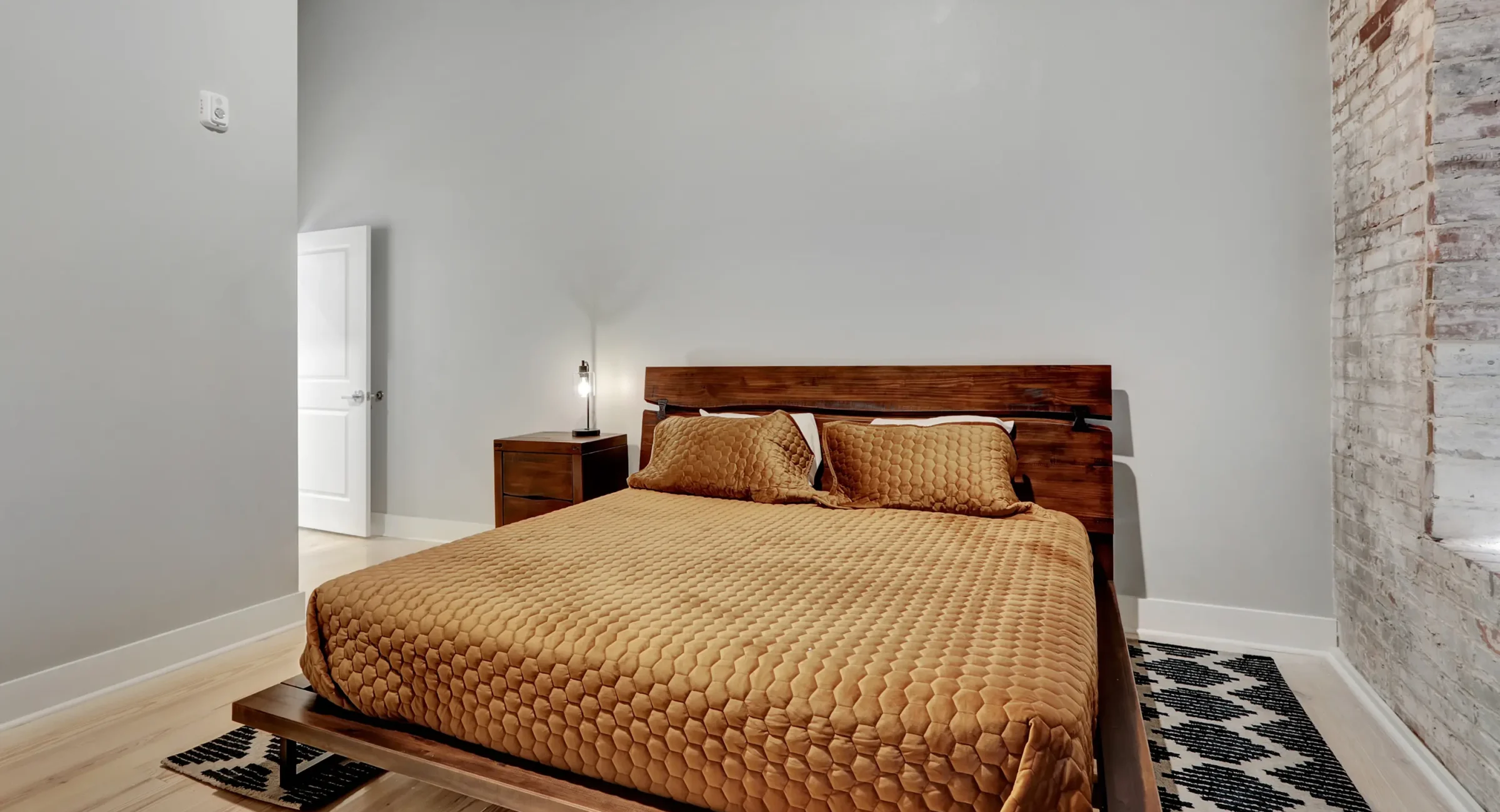 King bedroom with modern platform bed and brick accent wall Hot Springs vacation rental