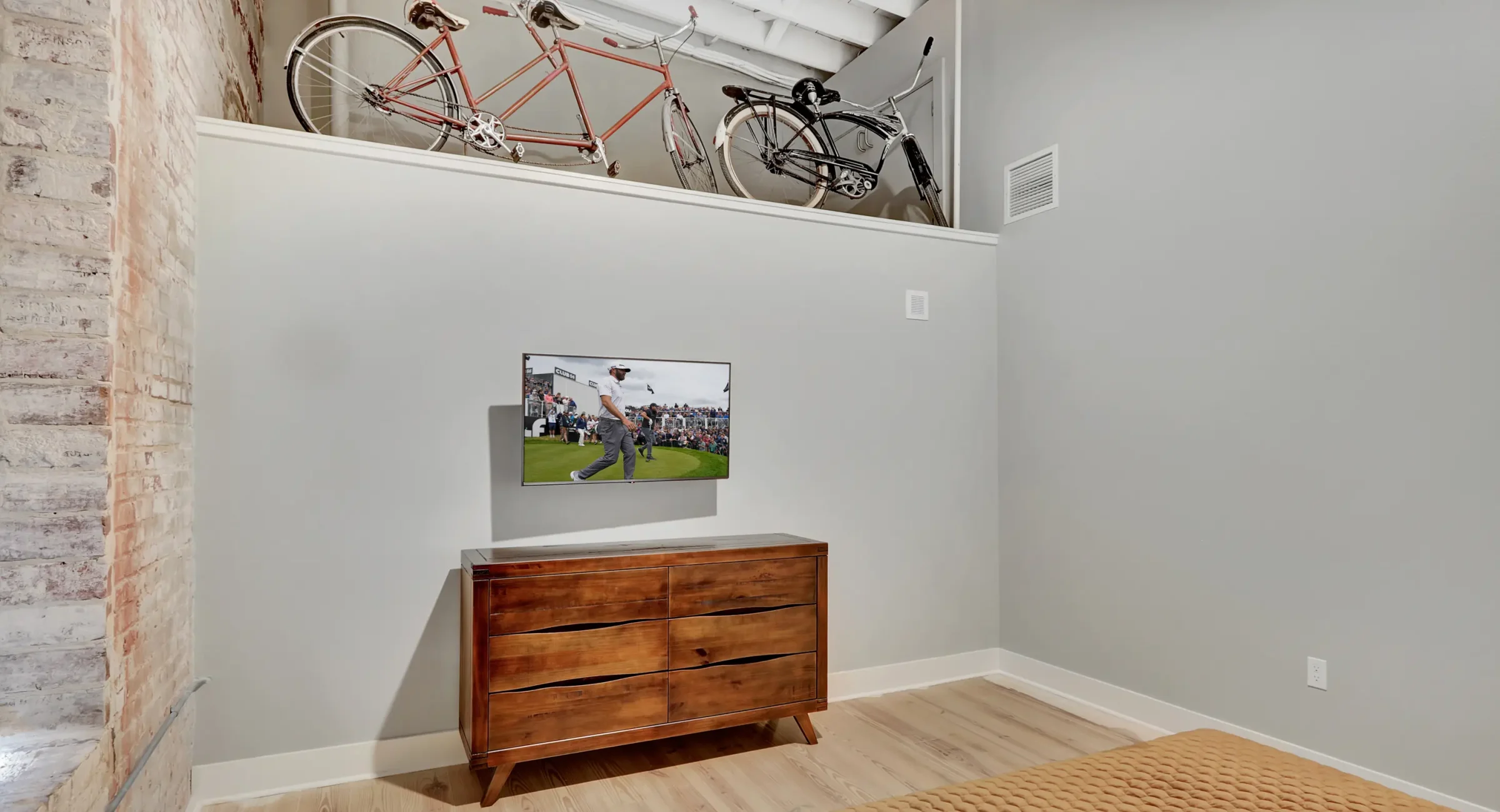 Bedroom dresser and mounted TV with vintage bicycle décor above Hot Springs AR boutique stays