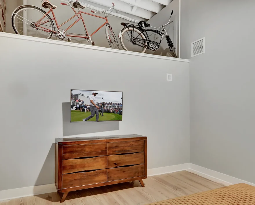Bedroom dresser and mounted TV with vintage bicycle décor above Hot Springs AR boutique stays