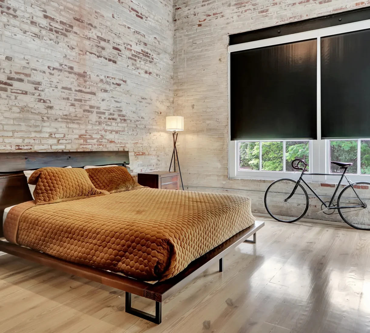 Bright industrial loft bedroom with exposed brick and large windows at Hot Springs accommodations