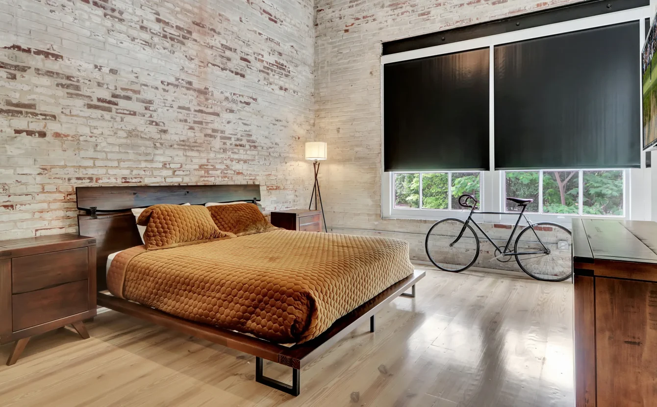 Bright industrial loft bedroom with exposed brick and large windows at Hot Springs accommodations