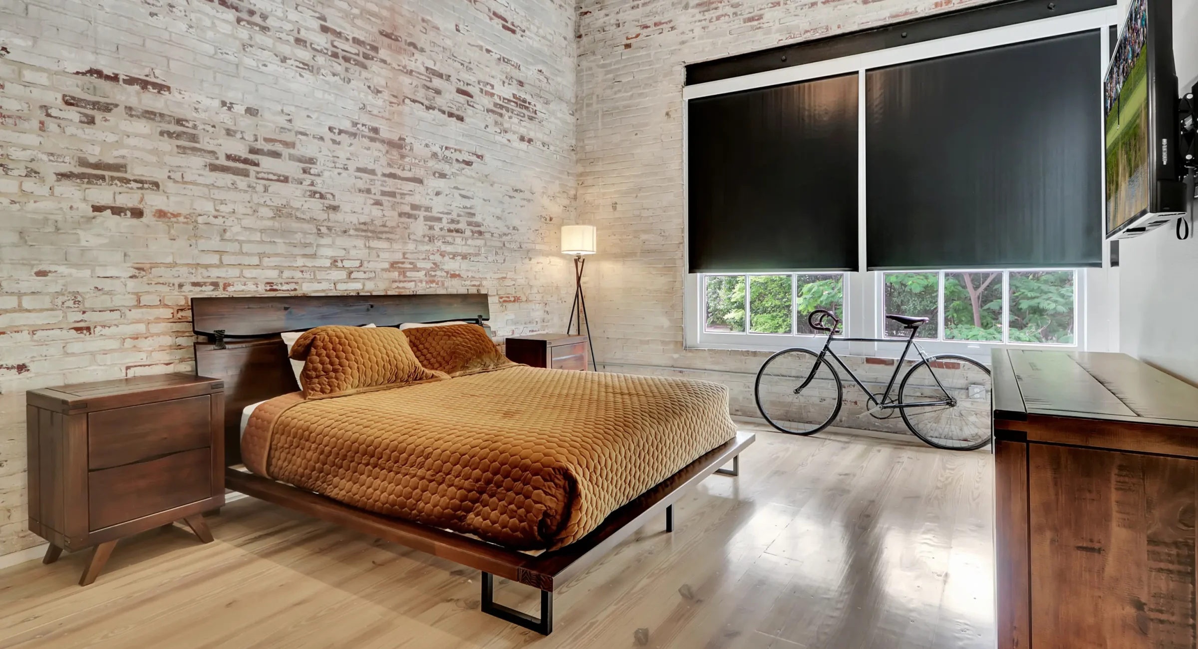 Bright industrial loft bedroom with exposed brick and large windows at Hot Springs accommodations