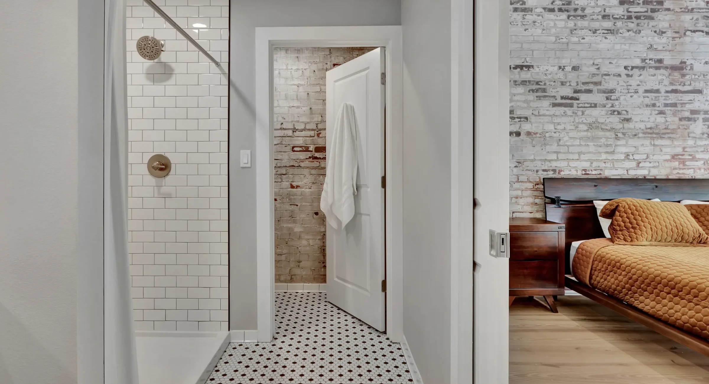 Shower and hallway view leading to exposed-brick bedroom at historic loft accommodations in Arkansas