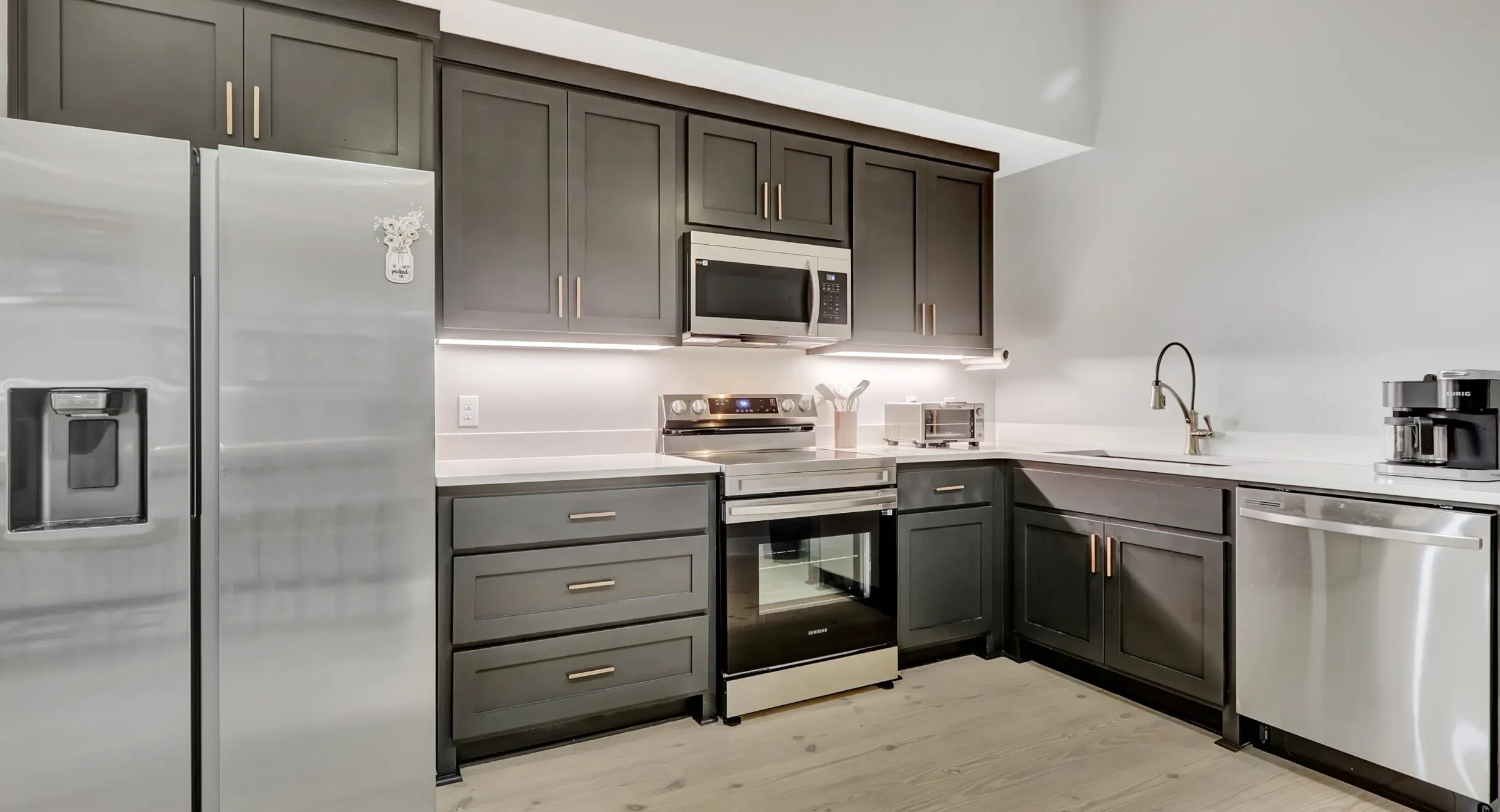 Modern kitchen inside a Hot Springs vacation rental, featuring stainless steel appliances, dark cabinetry, and quartz countertops
