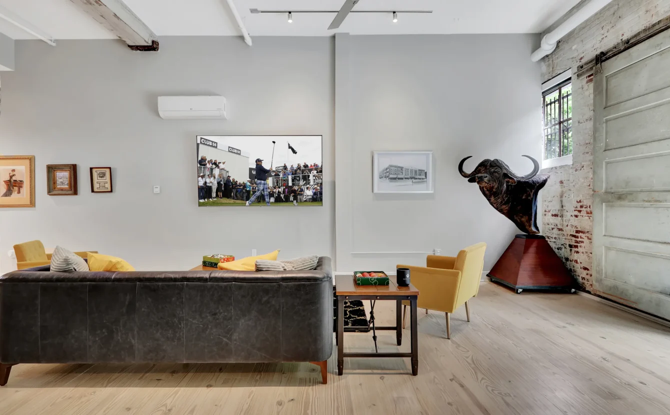 Stylish living space in a Hot Springs vacation rental with mounted TV, exposed beams, and unique artwork