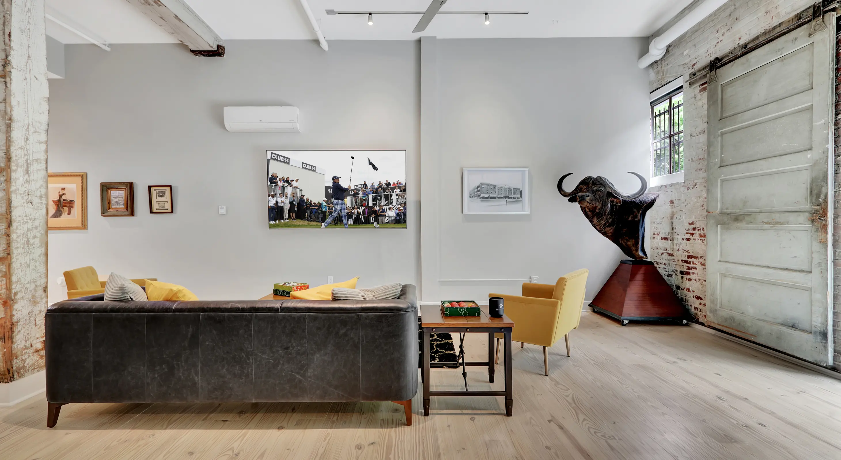 Stylish living space in a Hot Springs vacation rental with mounted TV, exposed beams, and unique artwork