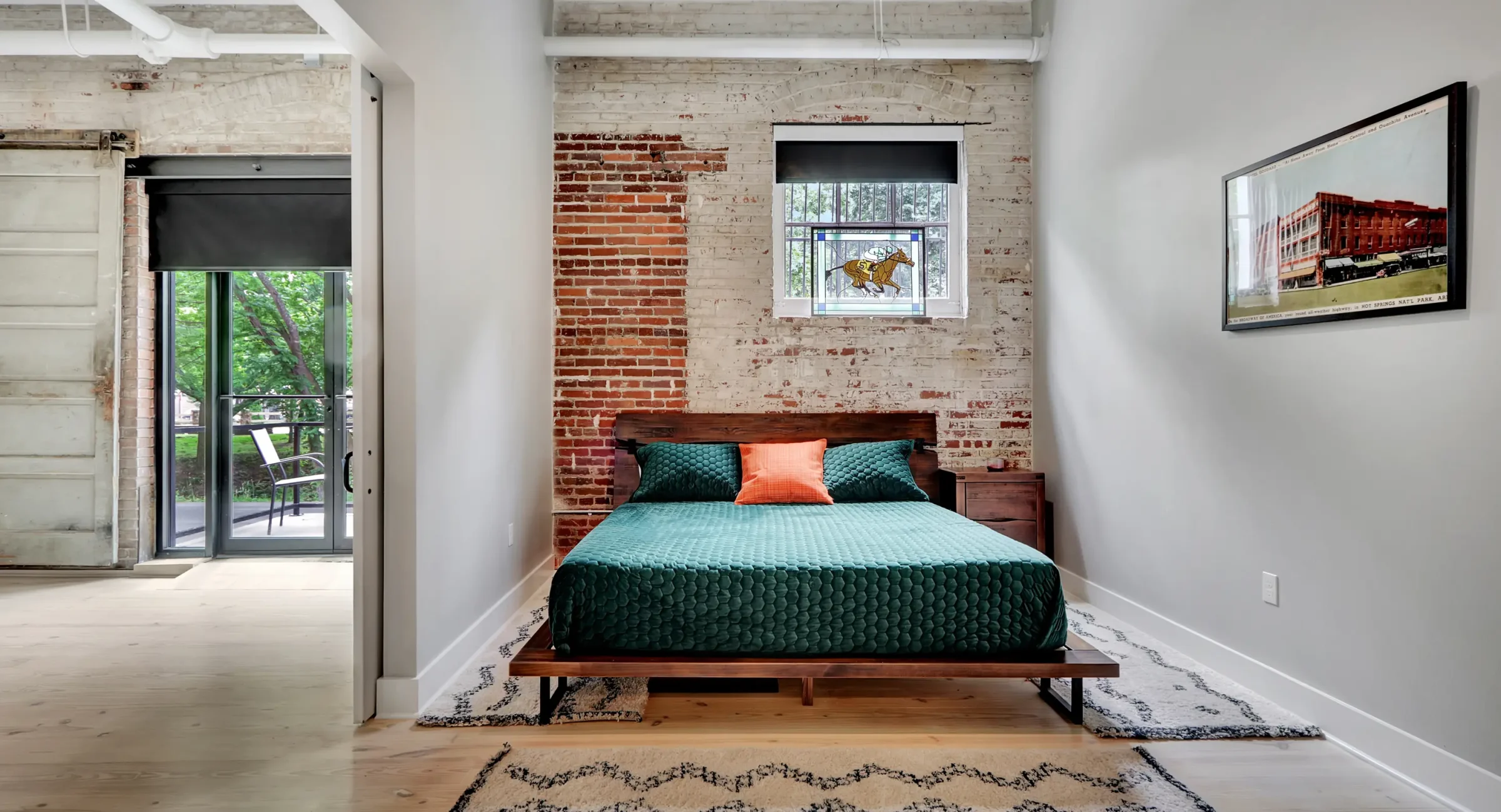 Loft-style bedroom in a Hot Springs rental with brick accents and sliding doors opening to the main living space