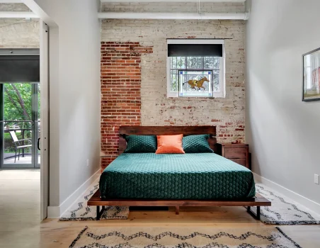 Loft-style bedroom in a Hot Springs rental with brick accents and sliding doors opening to the main living space
