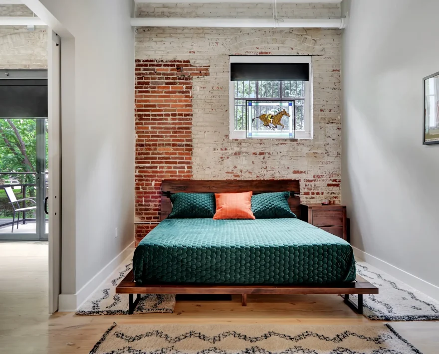 Loft-style bedroom in a Hot Springs rental with brick accents and sliding doors opening to the main living space