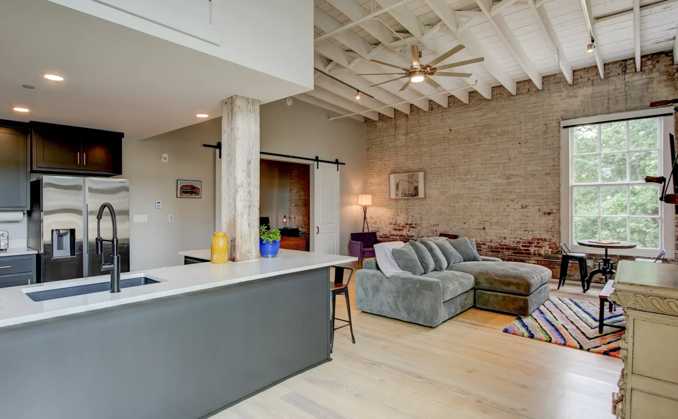 Open-concept loft rental in Hot Springs featuring a modern kitchen, large island seating, exposed brick walls, and spacious living area