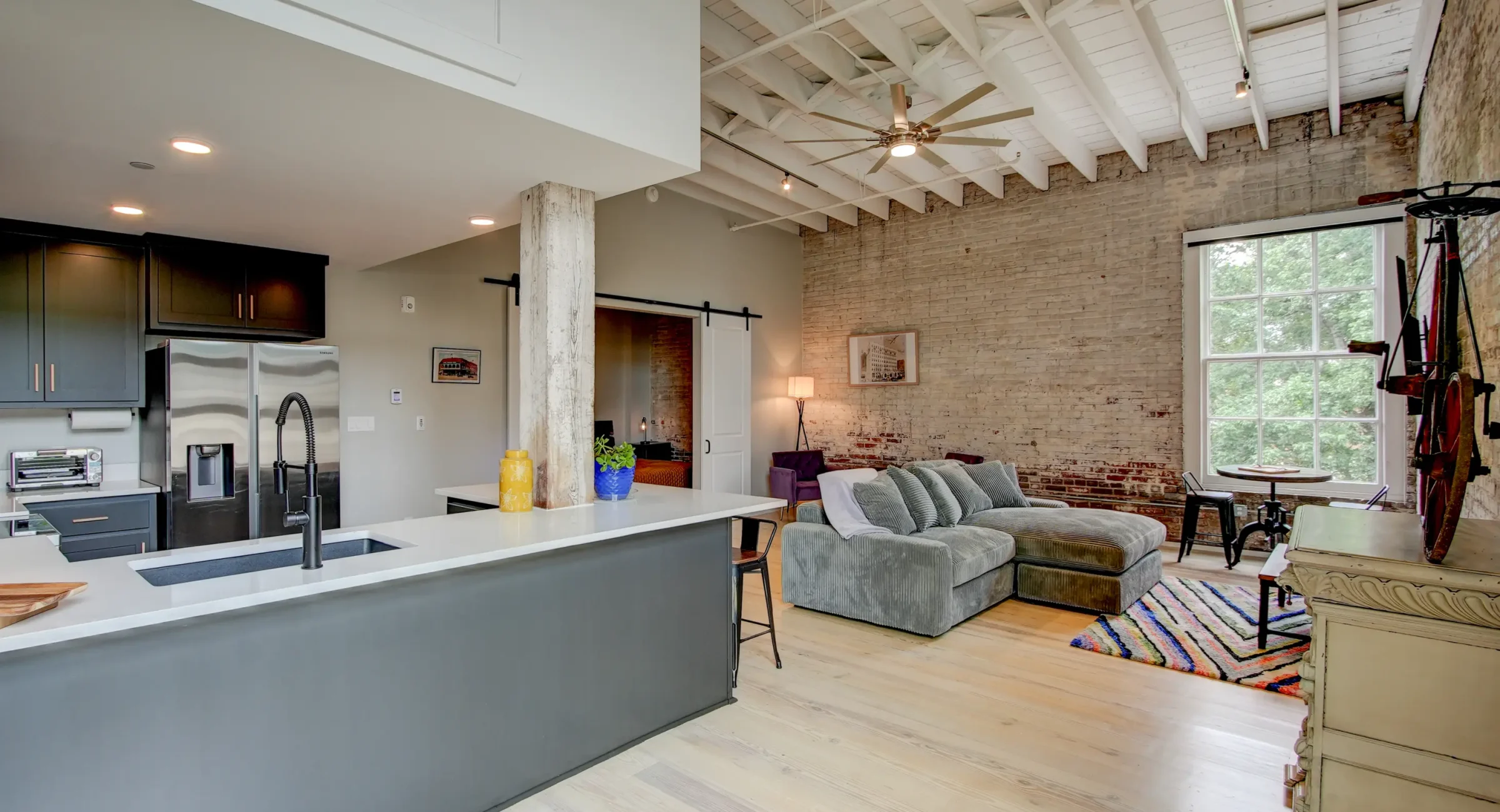 Open-concept loft rental in Hot Springs featuring a modern kitchen, large island seating, exposed brick walls, and spacious living area