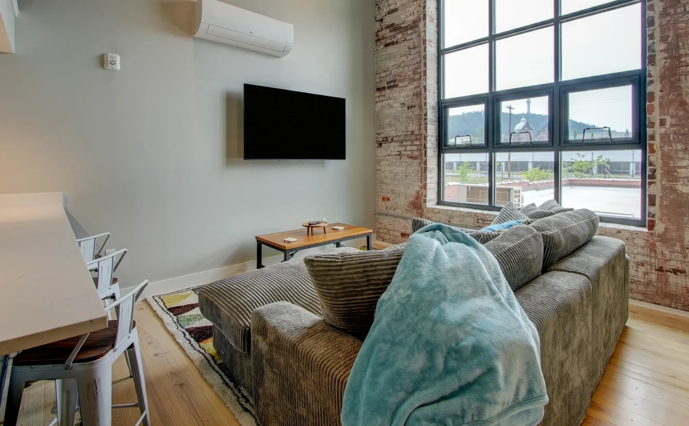 Open living area with exposed brick and large windows at downtown lodging near Hot Springs National Park