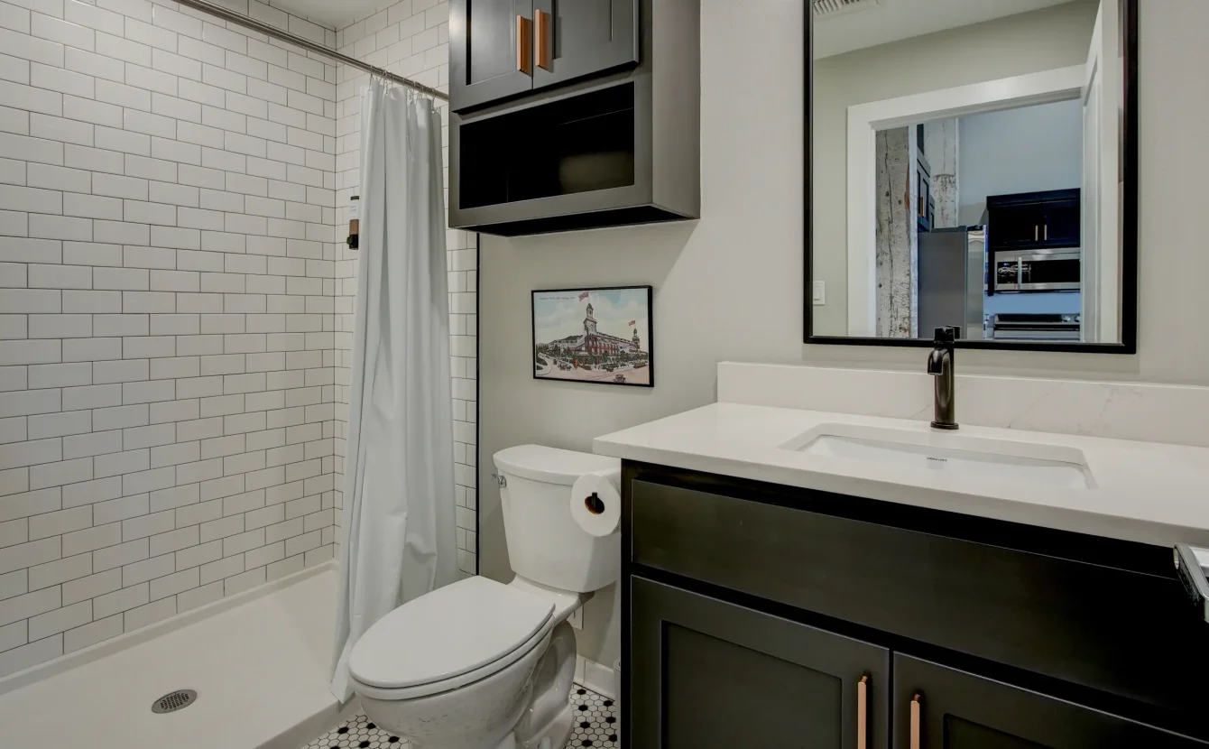 Bathroom inside The Como unit with subway-tile shower, dark cabinetry, and modern fixtures
