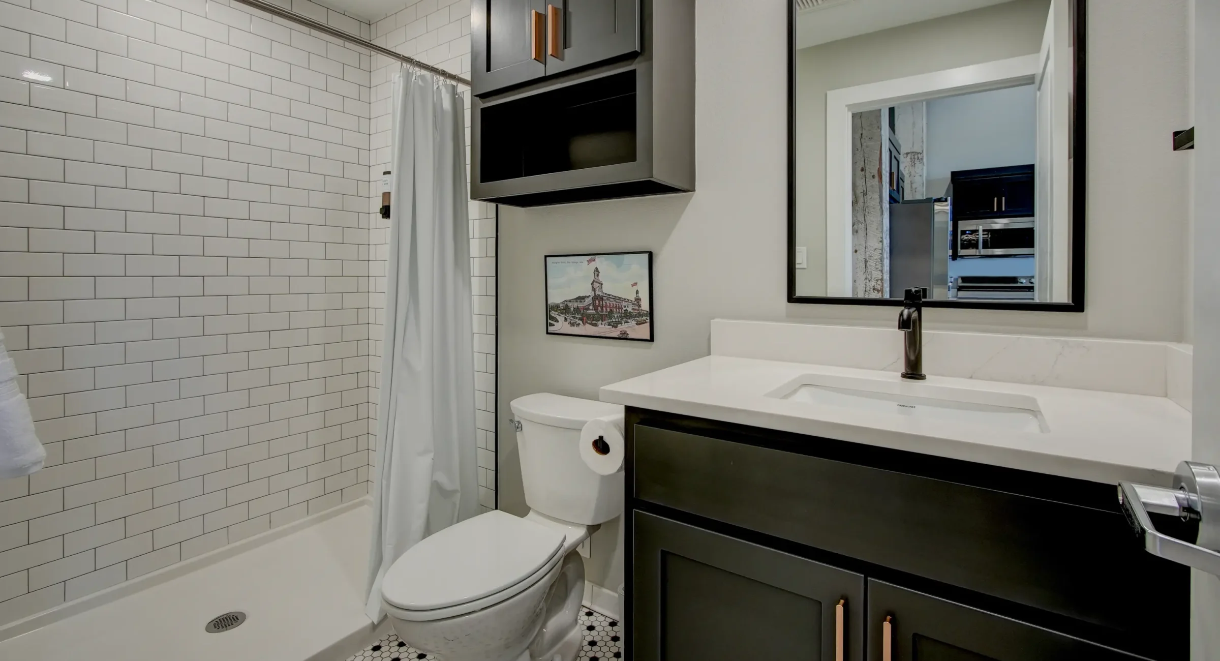 Bathroom inside The Como unit with subway-tile shower, dark cabinetry, and modern fixtures