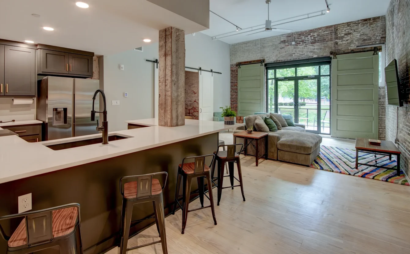 Open-concept loft rental in Hot Springs featuring a modern kitchen, large island seating, exposed brick walls, and spacious living area