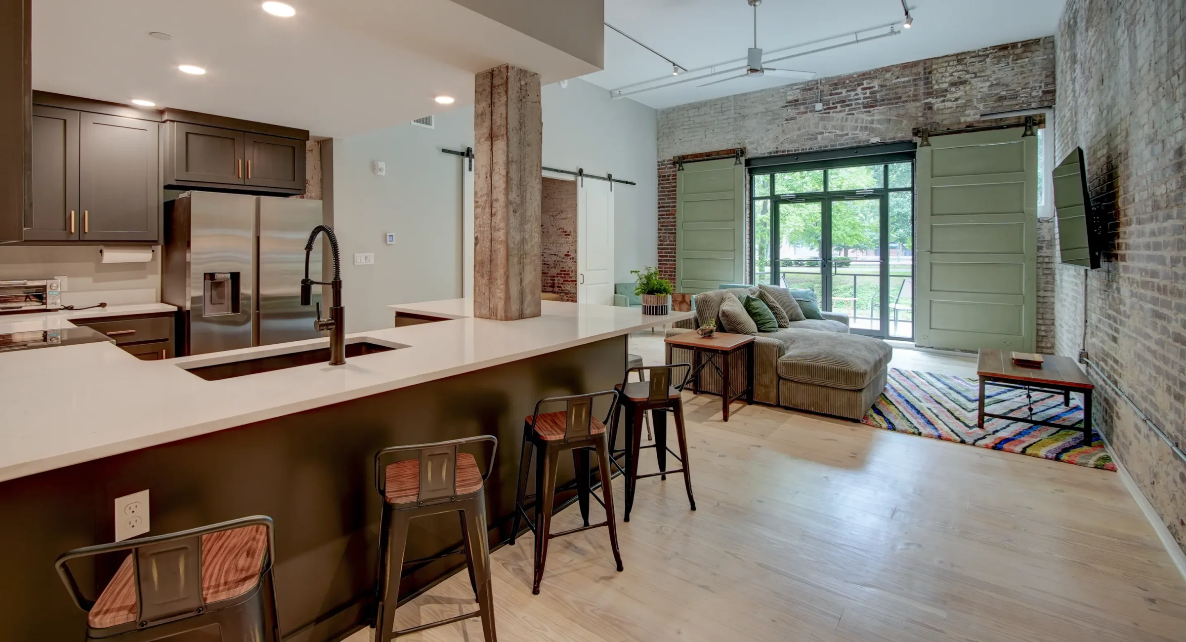 Open-concept loft rental in Hot Springs featuring a modern kitchen, large island seating, exposed brick walls, and spacious living area
