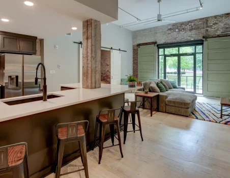 Open-concept loft rental in Hot Springs featuring a modern kitchen, large island seating, exposed brick walls, and spacious living area