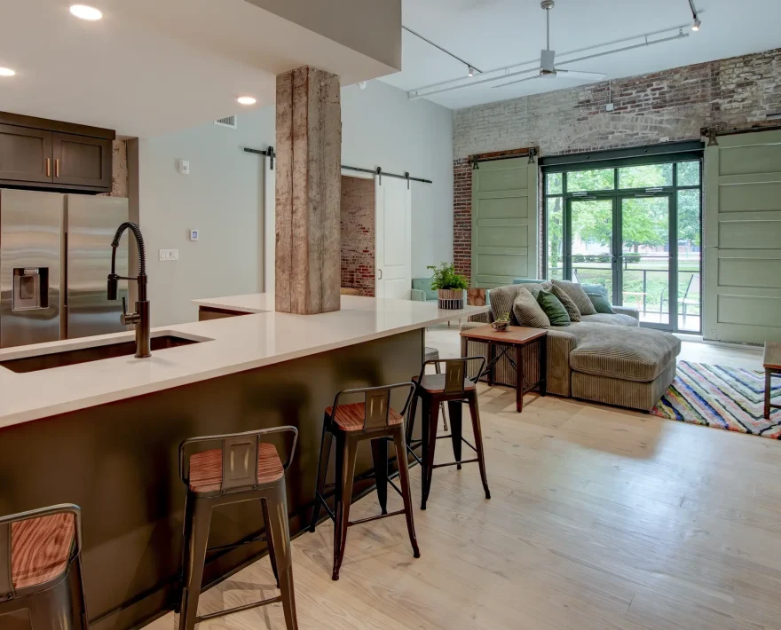 Open-concept loft rental in Hot Springs featuring a modern kitchen, large island seating, exposed brick walls, and spacious living area