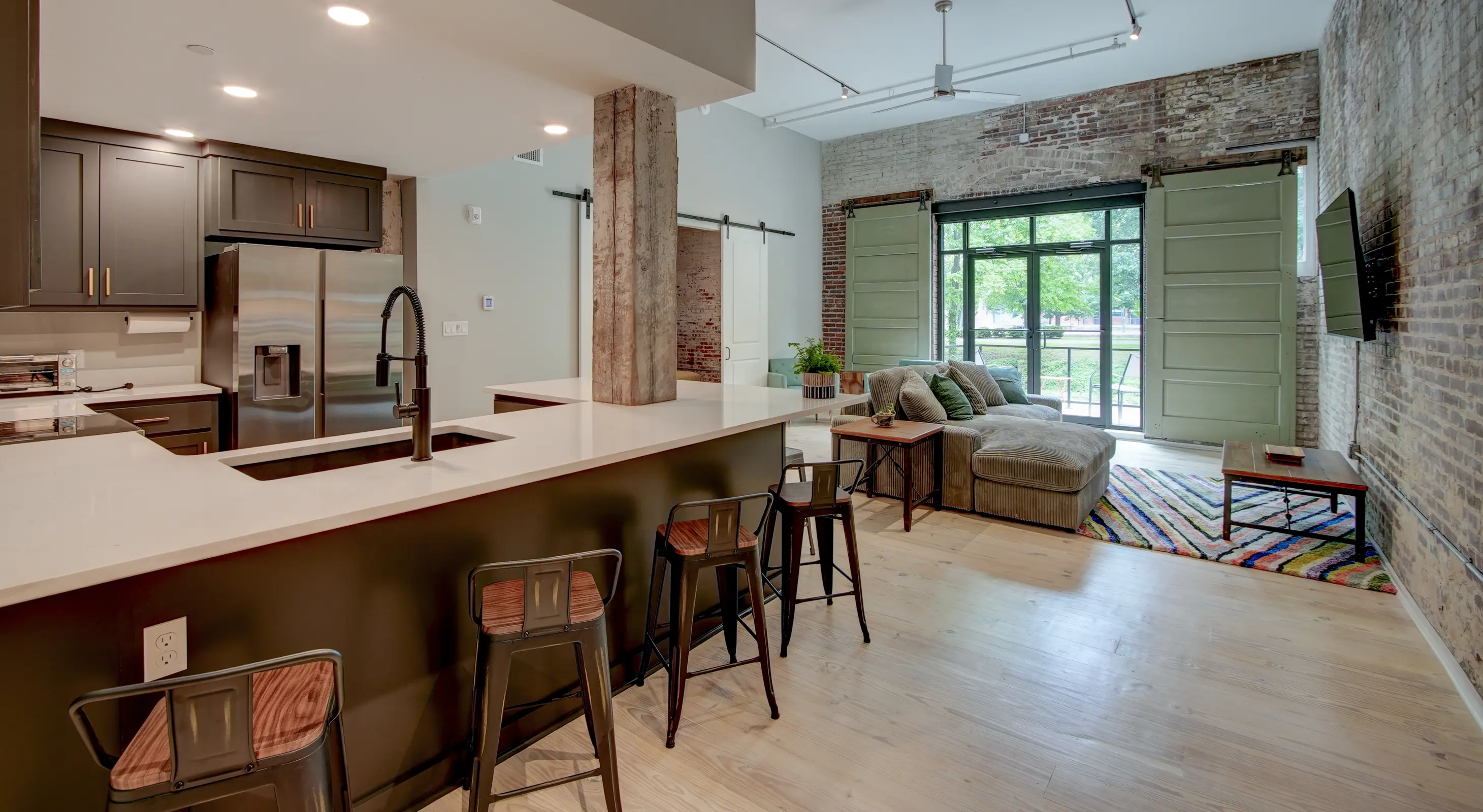 Open-concept loft rental in Hot Springs featuring a modern kitchen, large island seating, exposed brick walls, and spacious living area.