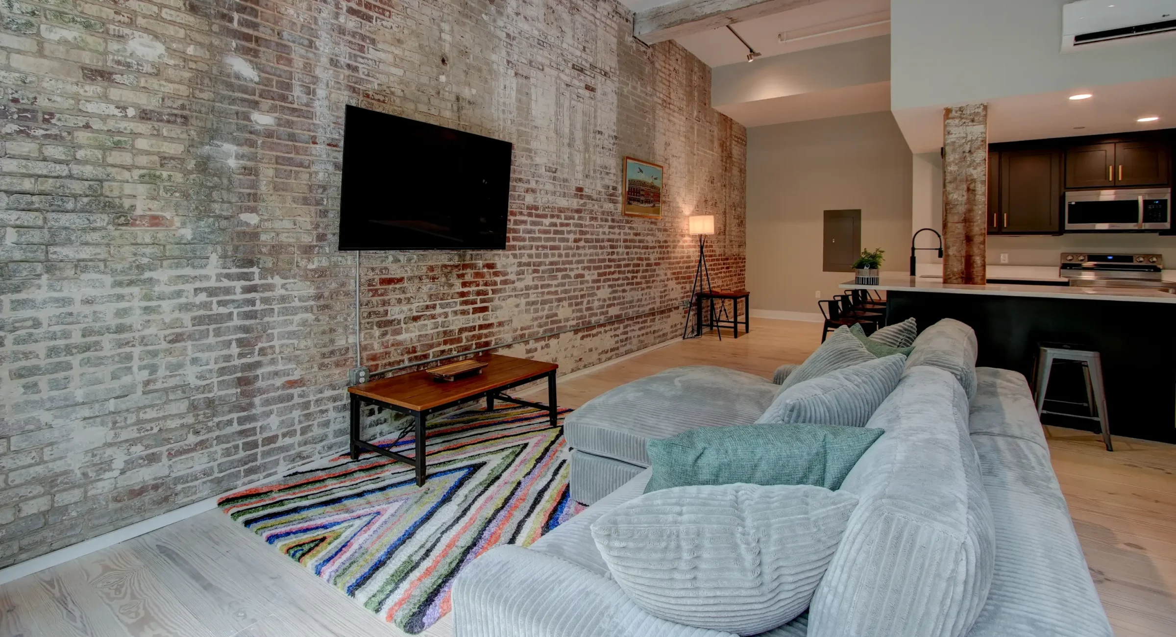 Cozy living area in a renovated Hot Springs loft featuring exposed brick, a mounted TV, and modern furnishings