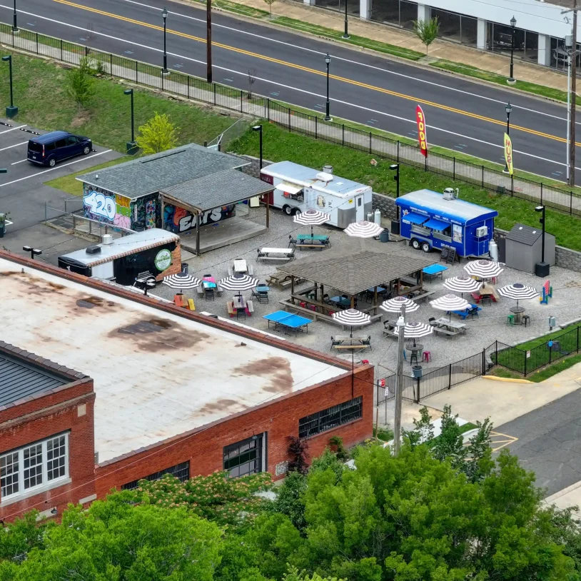 Detailed aerial of the property’s exterior, including its food court with food trucks, parking areas, and restored brick architecture in central Hot Springs