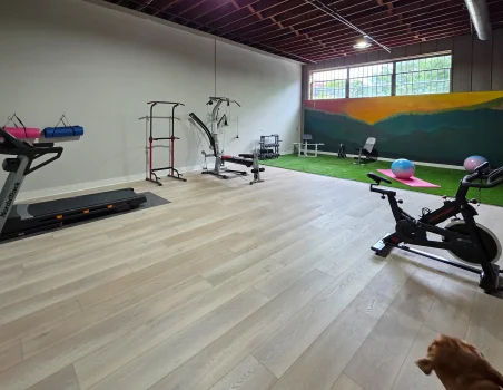 Onsite fitness studio with treadmill, strength equipment, and open workout space inside a renovated industrial loft property