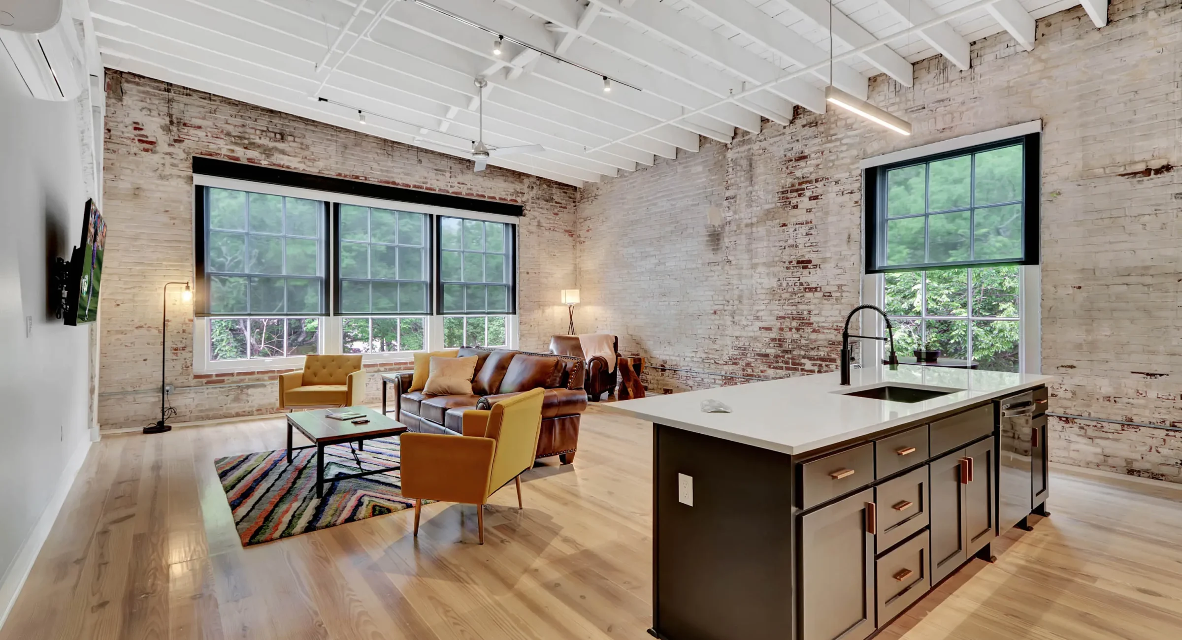 Open-concept loft living space with exposed brick and modern kitchen in Hot Springs