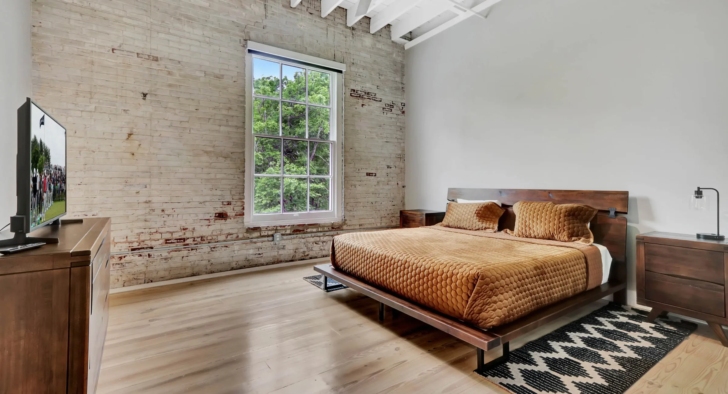 Primary bedroom with king bed, exposed brick, and natural light