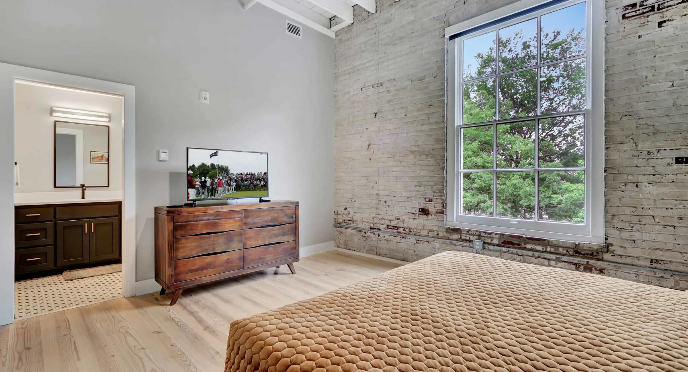 Bedroom with brick accent wall and ensuite bathroom access