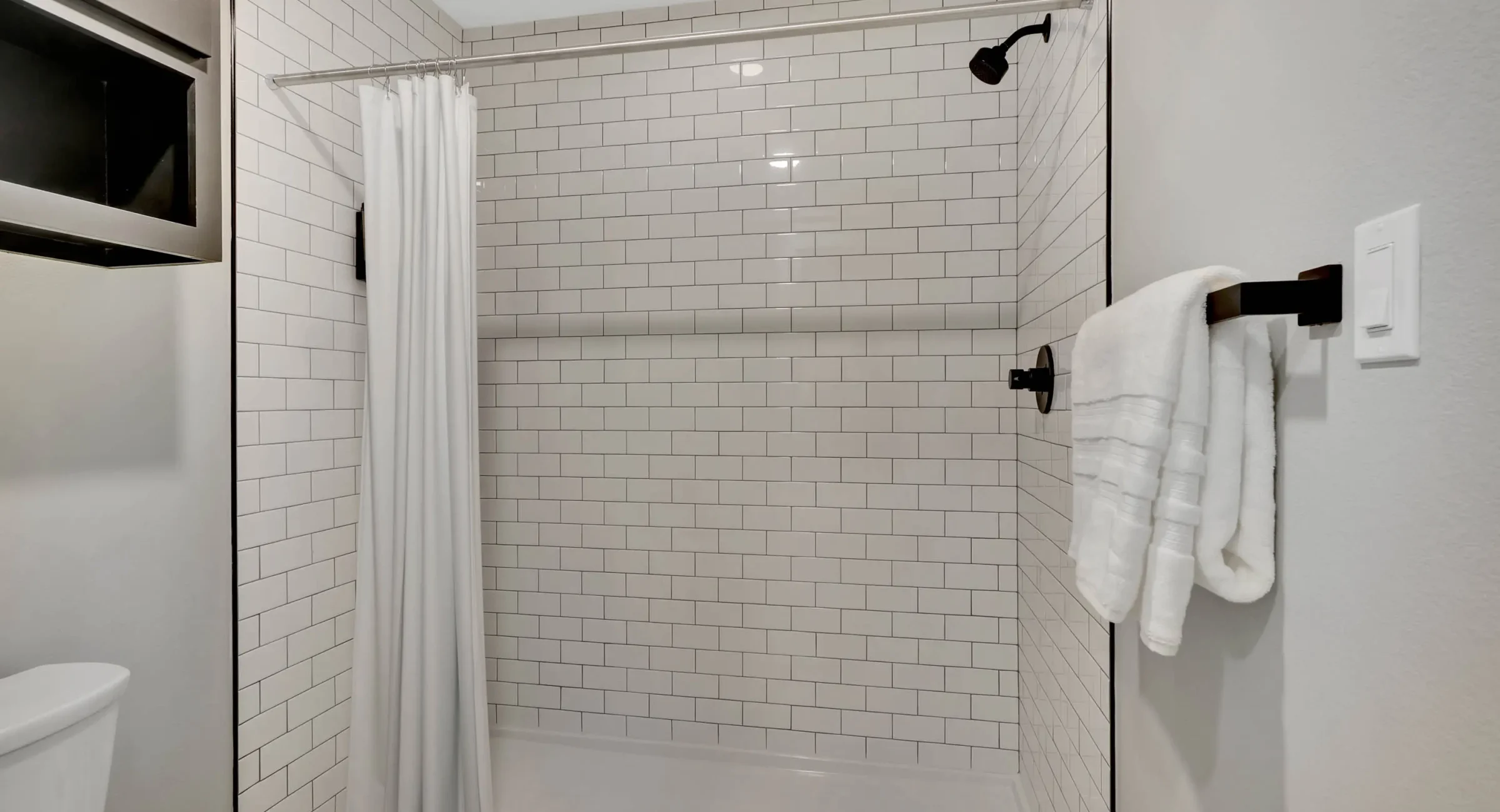 Walk-in shower with white subway tile and matte black fixtures