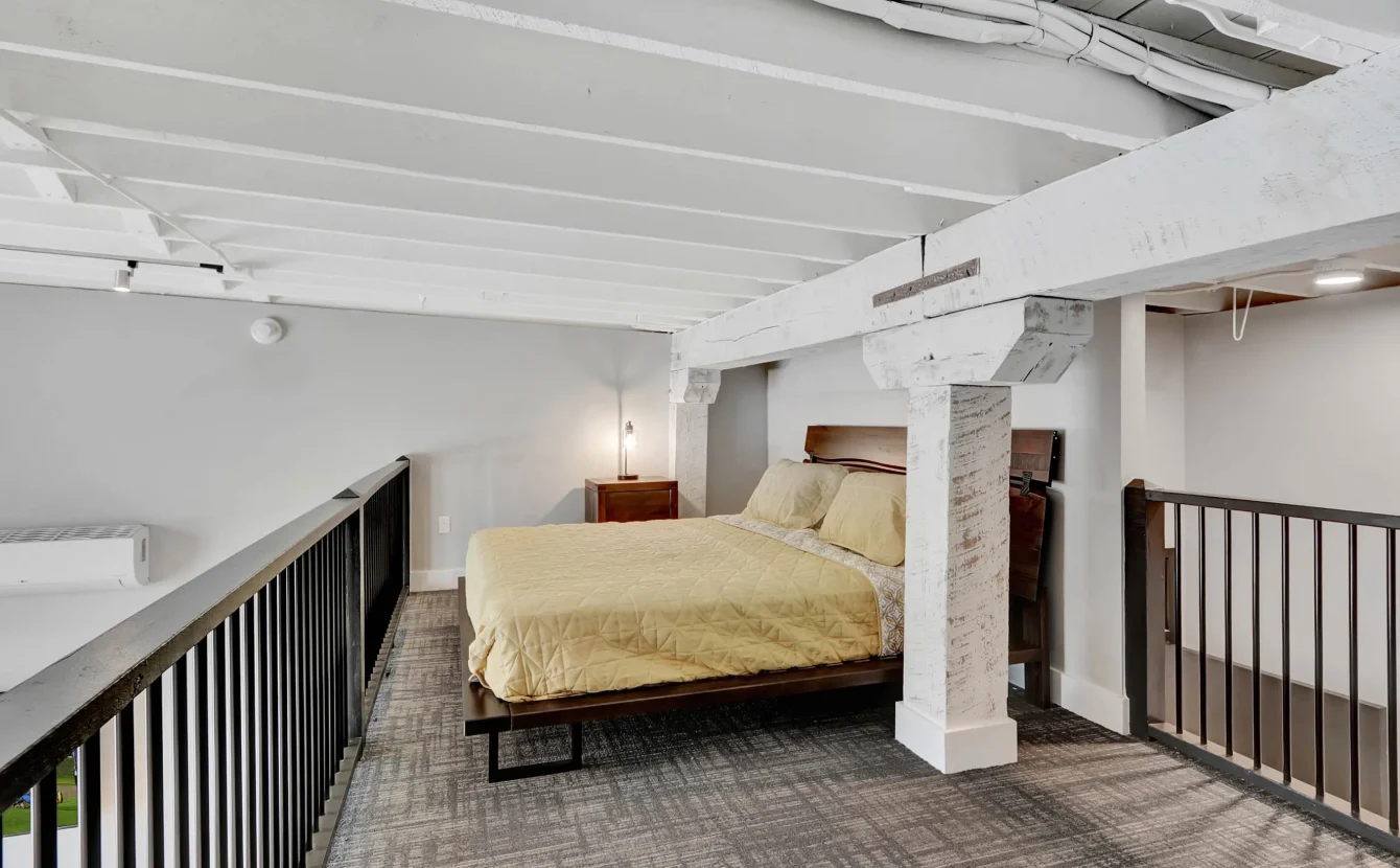 Loft bedroom on upper level with exposed beams in downtown Hot Springs lodging