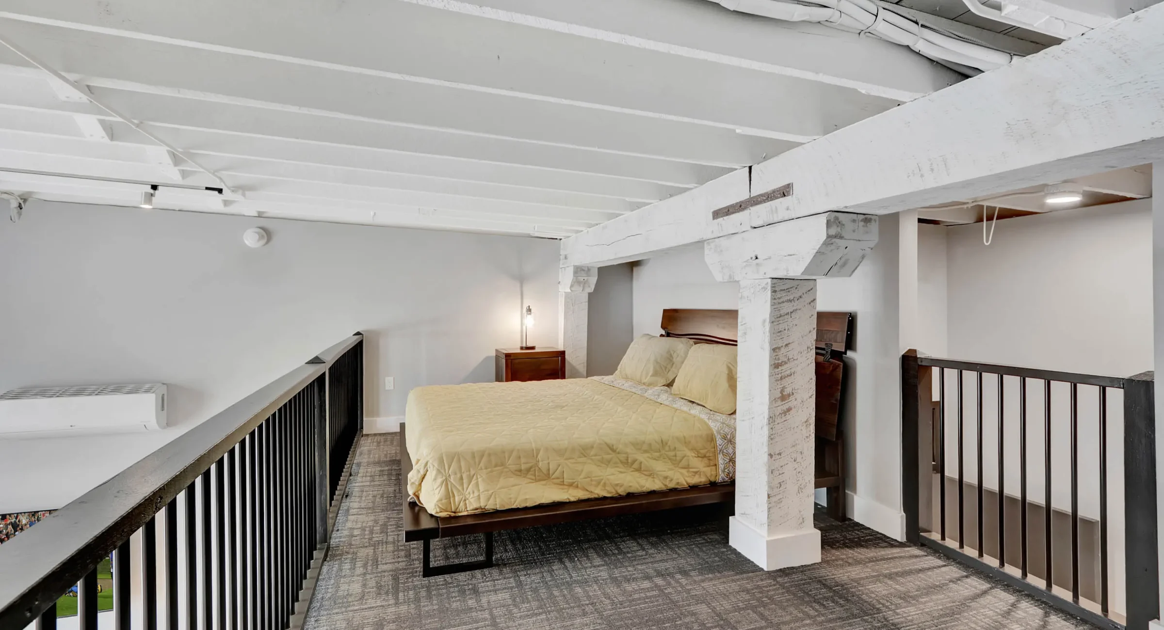 Loft bedroom on upper level with exposed beams in downtown Hot Springs lodging